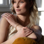 Elegant woman wearing sustainable Diamond Station Bracelet that is made of ethical lab-grown diamonds and recycled solid gold.