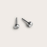 A pair of silver stud earrings featuring small, round diamonds set in a smooth, rounded bezel setting. The simple yet elegant design of the earrings showcases the diamonds at the center, giving them a subtle sparkle.