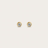 A pair of gold stud earrings featuring round diamonds set in a smooth, circular bezel setting. The earrings offer a simple and elegant look, with the diamonds placed in the center to provide a subtle shine.
