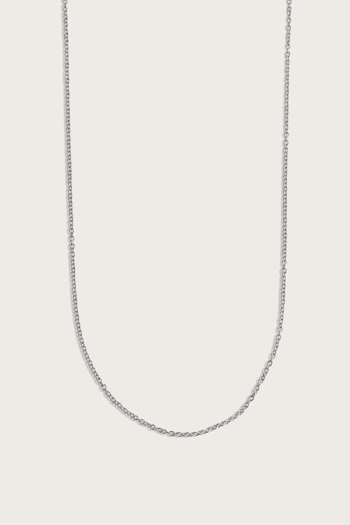 Simple silver chain necklace displayed on a light beige background.