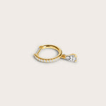 Gold hoop earring adorned with pavé-set diamonds and a dangling pear-shaped diamond, displayed on a light beige background.