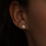 Close-up of a woman's ear wearing a single round diamond stud earring.