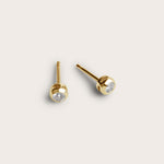 A pair of gold stud earrings featuring small, round diamond stones set in a smooth, rounded bezel setting. The earrings are simple yet elegant, with the diamonds subtly placed at the center.






