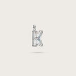 Silver pendant in the shape of the letter "K," adorned with sparkling gemstones, displayed on a light beige background.