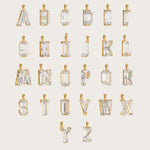 Collection of gold alphabet pendants, each adorned with sparkling gemstones, displayed on a light beige background.