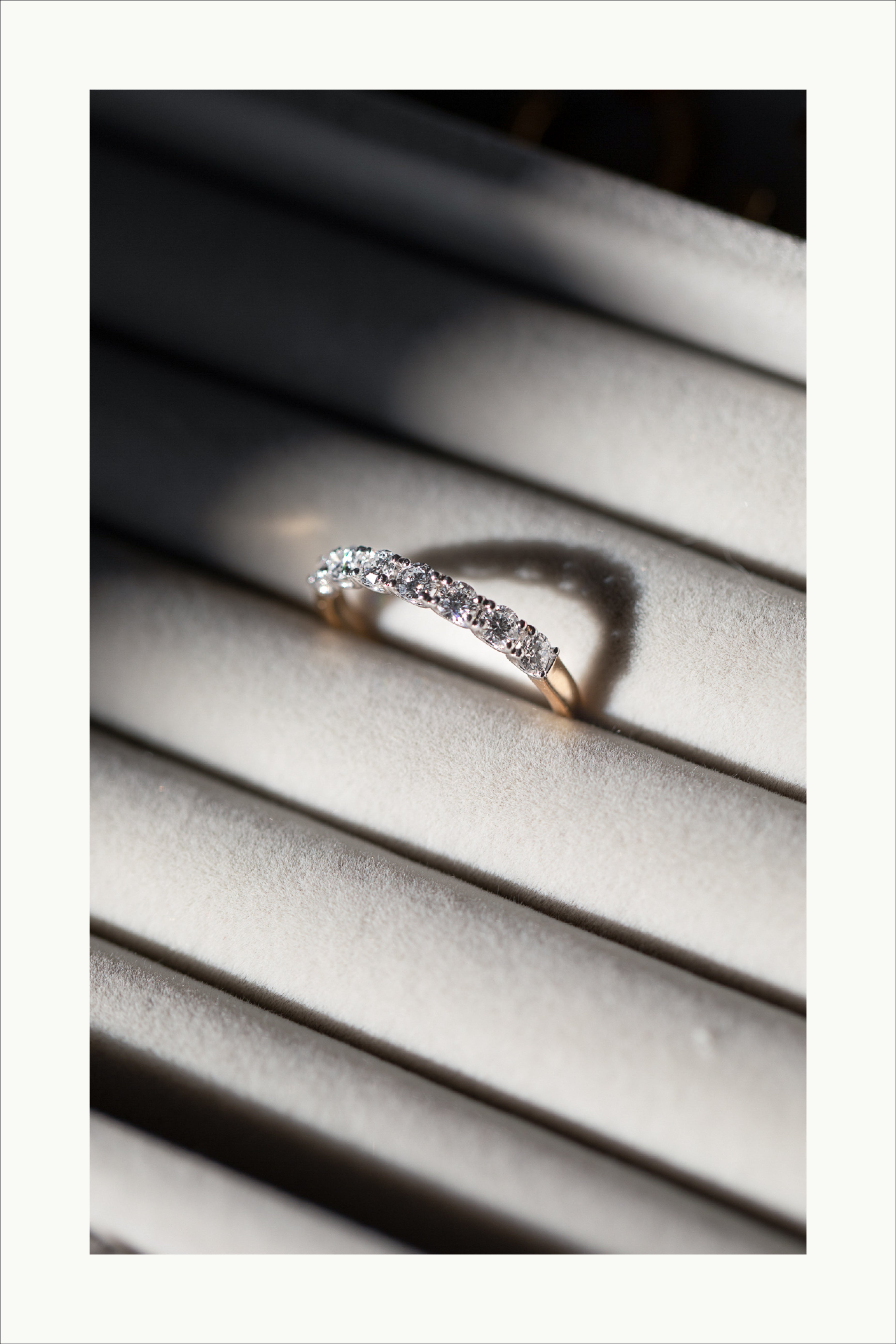 Diamond-studded gold ring elegantly displayed on a velvet-lined jewelry holder, illuminated by soft sunlight.