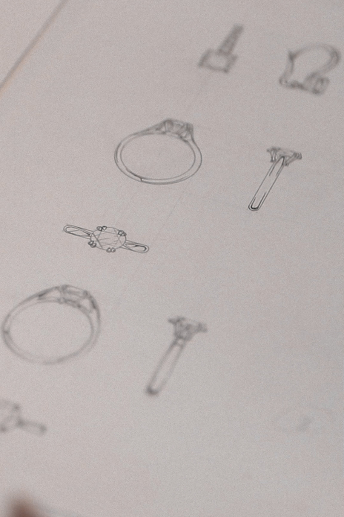 Sketches of various ring designs drawn on a sheet of paper, showcasing detailed outlines and side profiles of jewelry concepts.