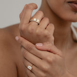 A beautiful shot of a model's crossed hands, styled with a yellow gold KARAAT emerald-cut solitaire ring on her ring finger and a bold ring stack on her index finger.