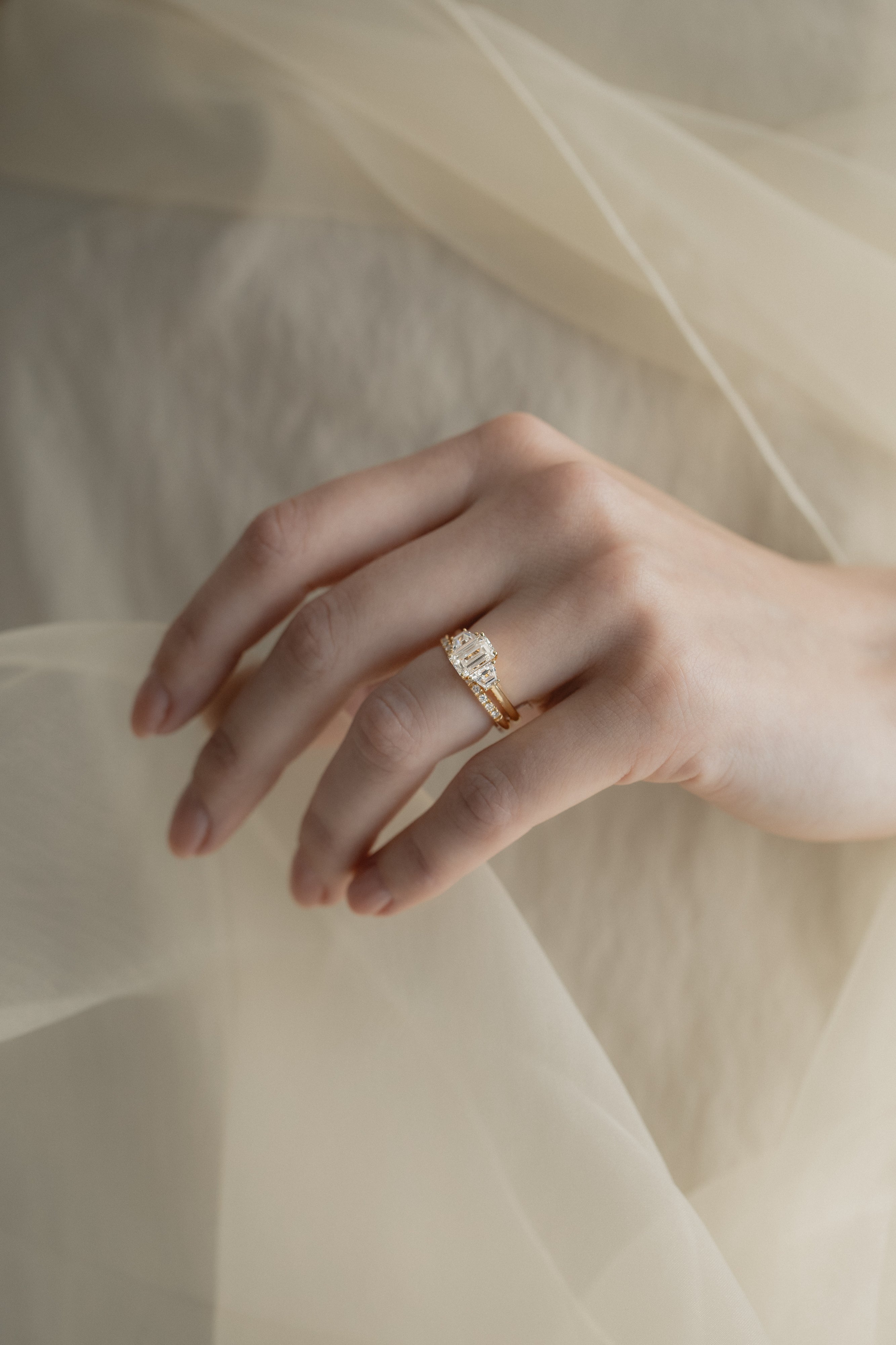 A KARAAT Emerald Trilogy diamond engagement ring in 18k white gold styled with a delicate organza dress.