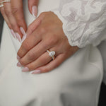 Elegant bridal lifestyle shot of a bride in a lace gown showcasing a modern bezel-set oval diamond engagement ring stacked with the Pavé Diamond Ring II in white gold.