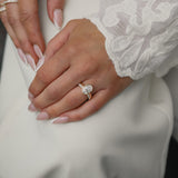 Elegant bridal lifestyle shot of a bride in a lace gown showcasing a modern bezel-set oval diamond engagement ring stacked with the Pavé Diamond Ring II in yellow gold.