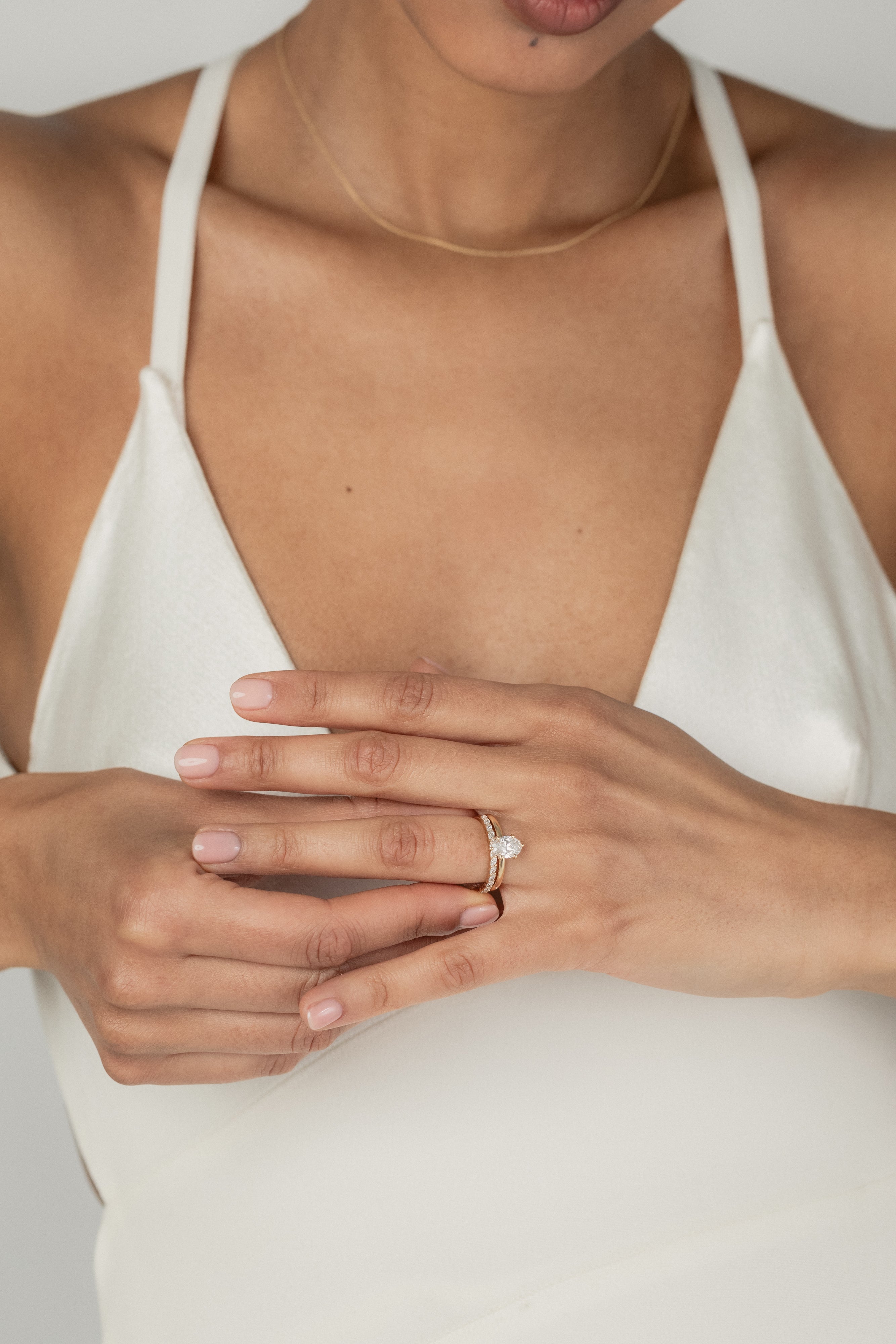 A model wearing the KARAAT Oval Six Prong Solitaire in 18k white gold, stacked with Marquise Half Eternity diamond wedding band.