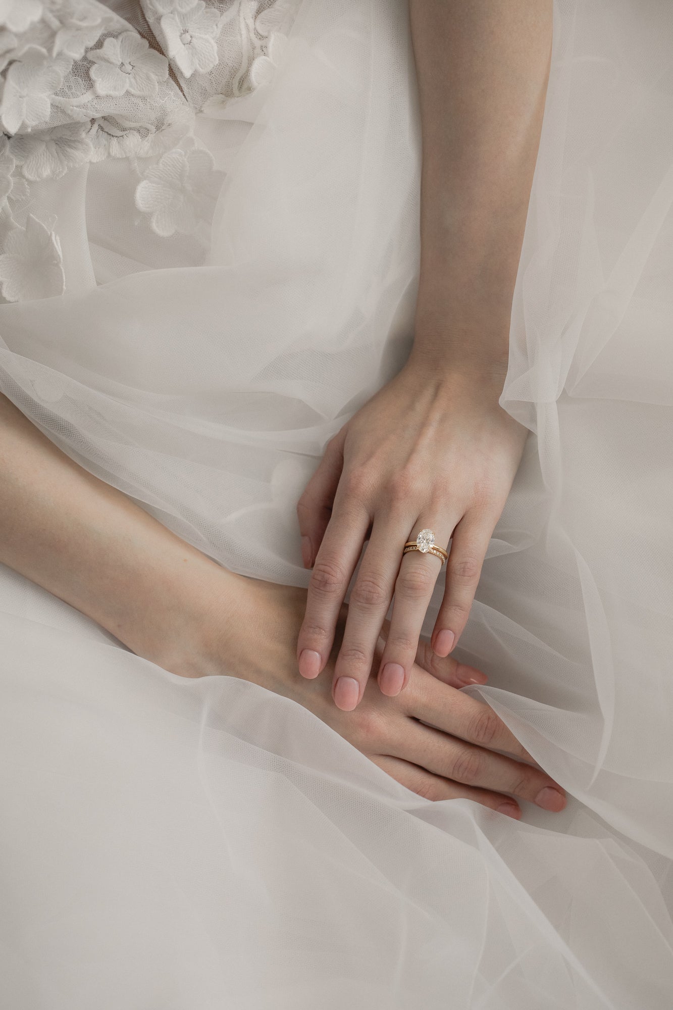 Bride wearing KARAAT Oval Solitaire diamond engagement ring in 18k yellow gold paired with a tulle wedding dress.
