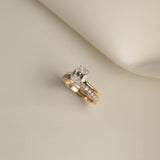 Still life shot of a white gold luxury bridal ring stack featuring a classic oval solitaire diamond engagement ring paired flush with the Pavé Diamond Ring II on a cream fabric background.