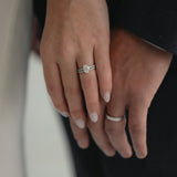 A close-up of a couple’s hands celebrating an engagement, featuring a KARAAT Oval Solitaire diamond ring with a pavé band in 18k rose gold.