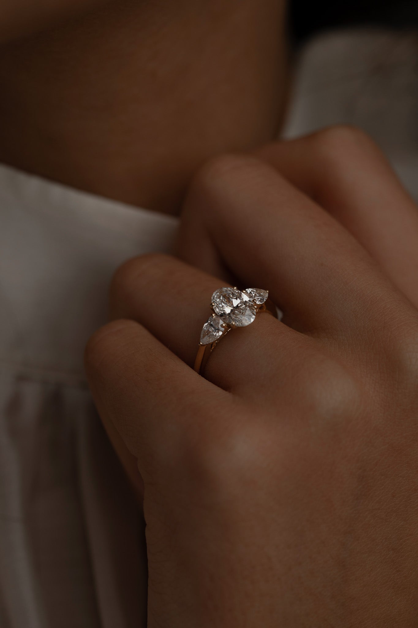 Macro close-up of a model's hand with the KARAAT Oval Trilogy ring in 18k white gold, highlighting the side-stone details.