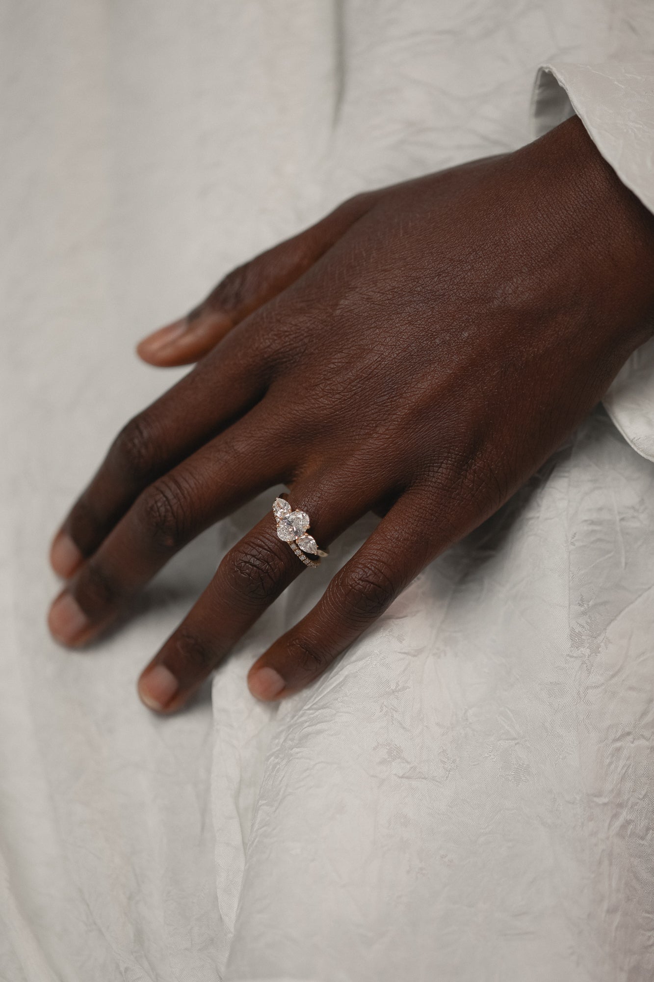 Model's hand wearing the KARAAT Oval Trilogy engagement ring in 18k rose gold, showing the three-stone proportions.