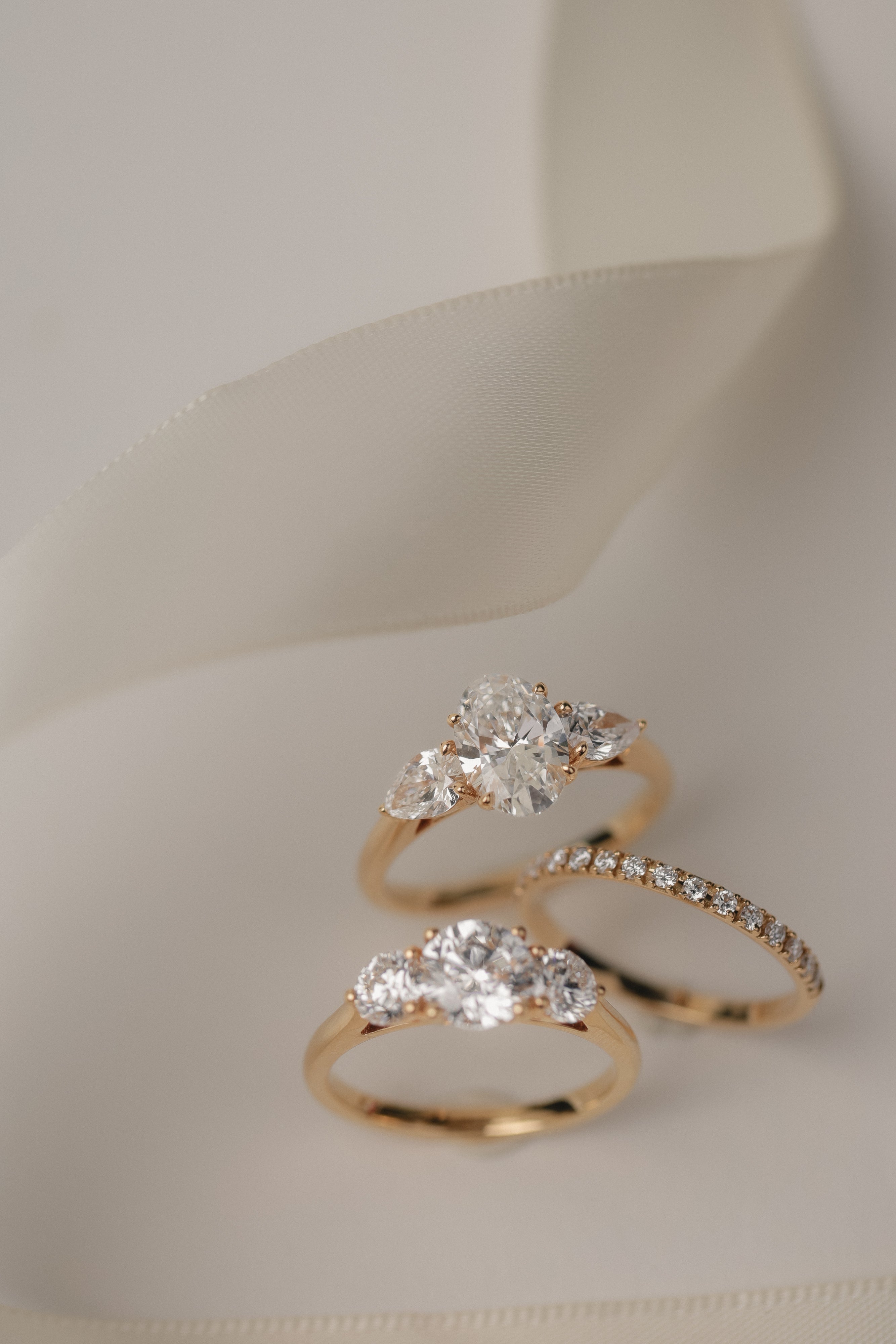 Product photography of the KARAAT Oval Trilogy in 18k yellow gold, detailing the precise three-stone setting.