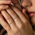 A close-up lifestyle image of a model displaying a delicate ring stack featuring multiple sizes of KARAAT white gold pavé diamond rings.