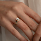 A detailed macro view of a yellow gold KARAAT pear-cut solitaire diamond engagement ring paired flawlessly with a sparkling pavé diamond wedding band on a model's hand.
