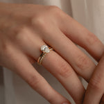 A detailed macro view of a white gold KARAAT pear-cut solitaire diamond engagement ring paired flawlessly with a sparkling pavé diamond wedding band on a model's hand.