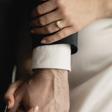 Couple holding hands, the woman wearing the Round and Pear Toi et Moi lab-grown diamond engagement ring in yellow gold