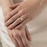 A model wearing a KARAAT Round Solitaire paired with a matching 18k white gold wedding band against a silk wedding dress.