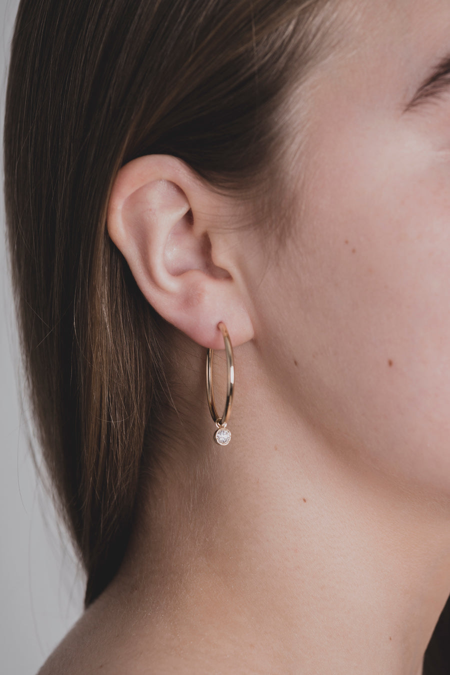 Scandinavian woman wearing modern diamond hoops, made of sustainable lab-grown diamonds and 18k solid gold. 