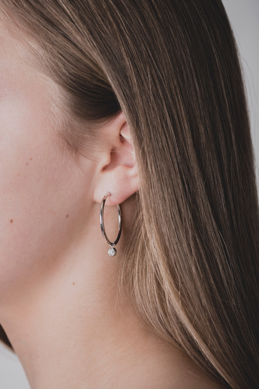 Scandinavian woman wearing modern diamond hoops, made of sustainable lab-grown diamonds and 18k solid gold. 