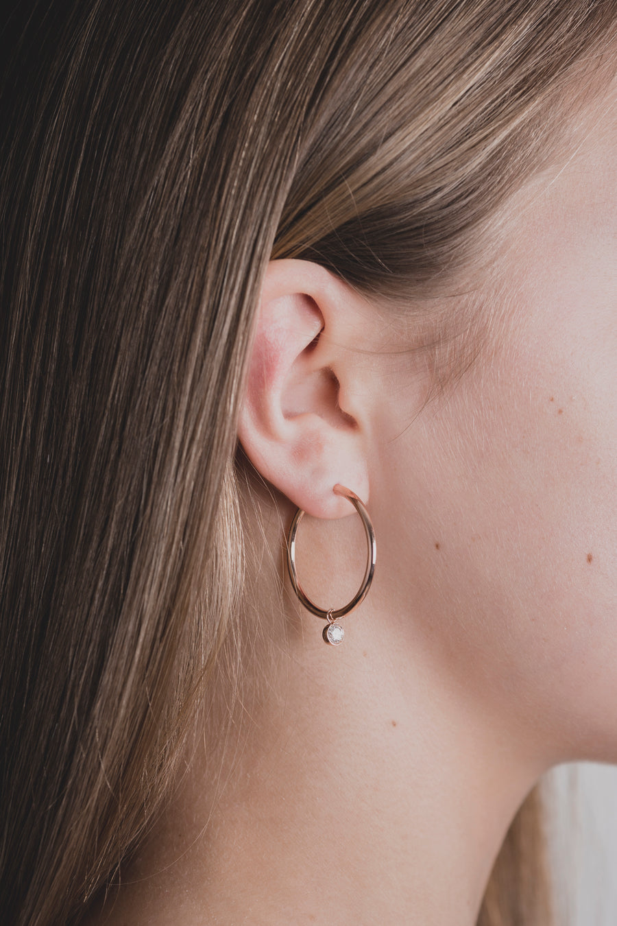 Scandinavian woman wearing modern diamond hoops, made of sustainable lab-grown diamonds and 18k solid gold. 