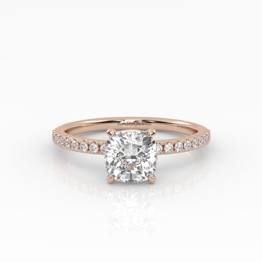Classic cushion shaped solitaire diamond ring with a rose gold band featuring pavé diamonds. 